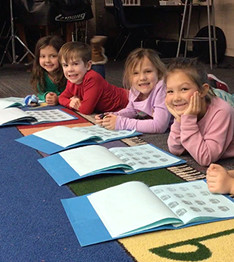 Students on the floor with workbooks